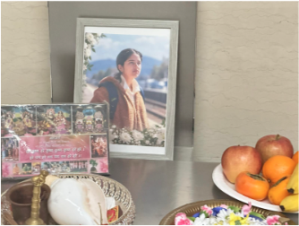 A memorial altar for Devika, with her photograph, flowers, and offerings.